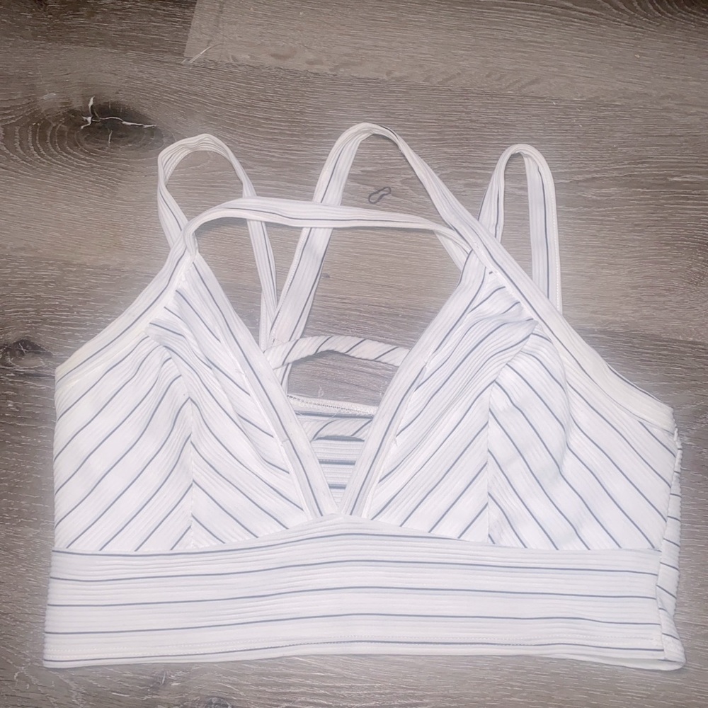 Striped white and black cropped top with crossed straps in the back .